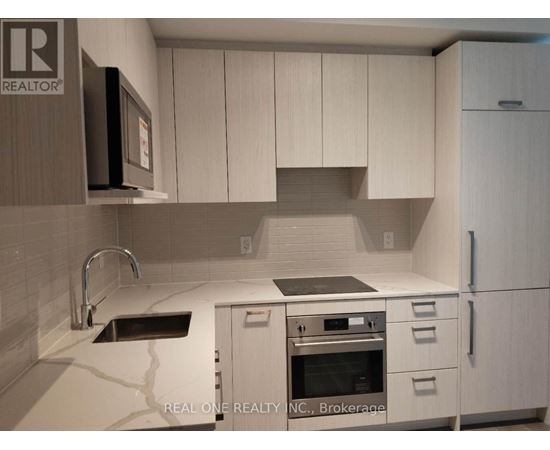 A kitchen with white cabinets and a black microwave.