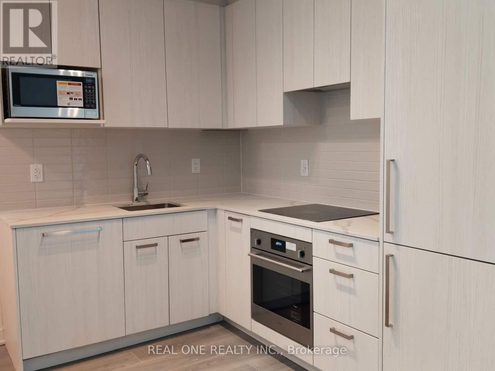 A kitchen with white cabinets and a microwave above the sink.