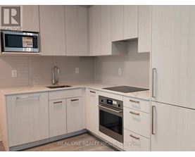 A kitchen with white cabinets and a microwave above the sink.
