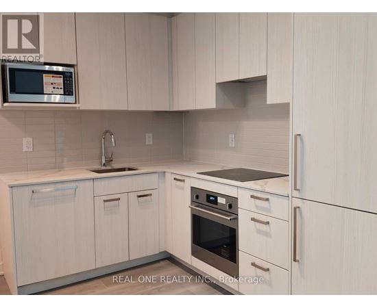A kitchen with white cabinets and a microwave above the sink.