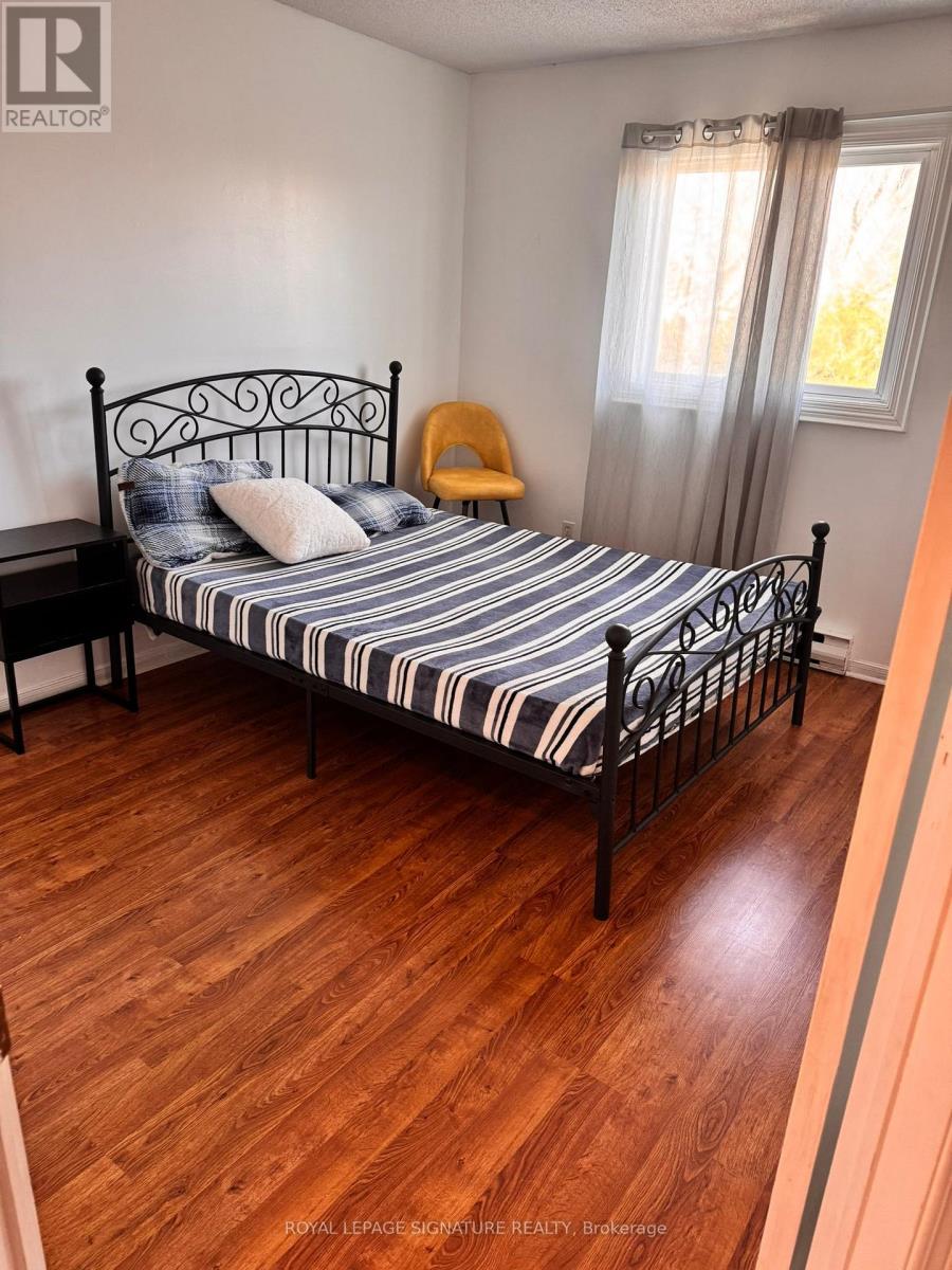 A bedroom with a bed, chair, and wooden floors.