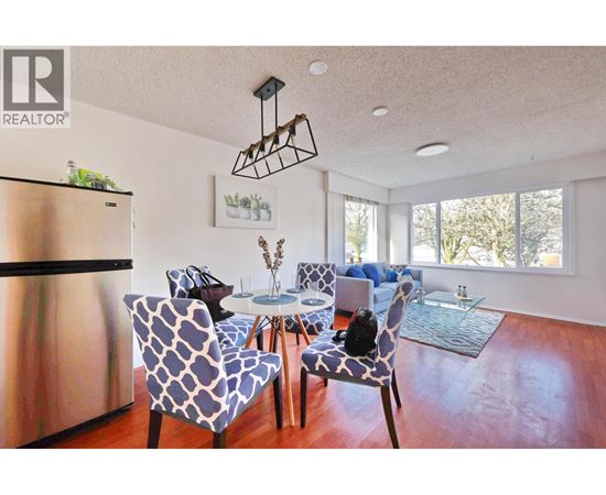 A modern dining room with a stainless steel refrigerator and a glass table.