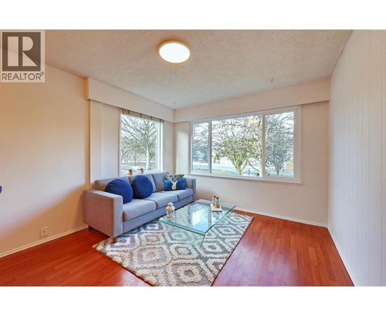 A living room with a grey couch and a rug.
