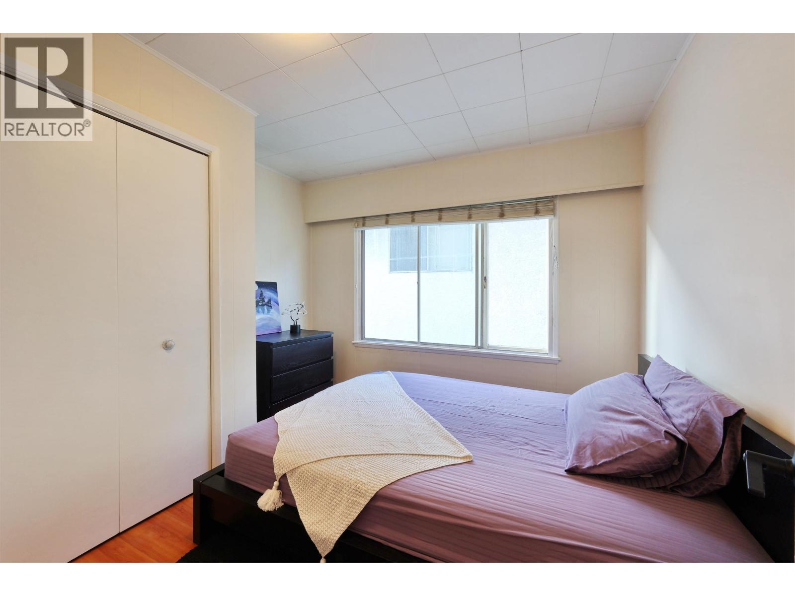A bedroom with a bed, nightstand, and window.