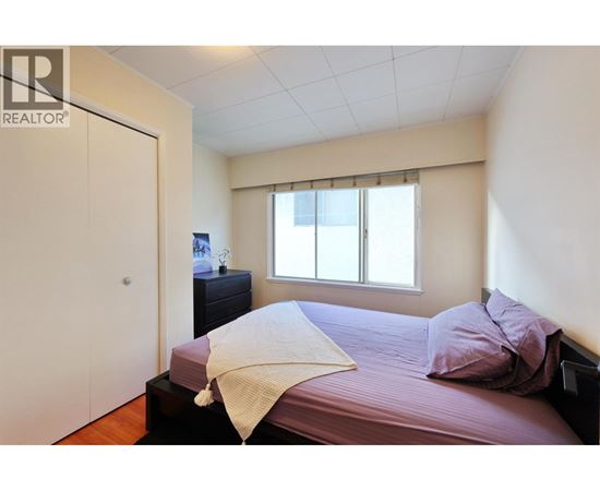A bedroom with a bed, nightstand, and window.