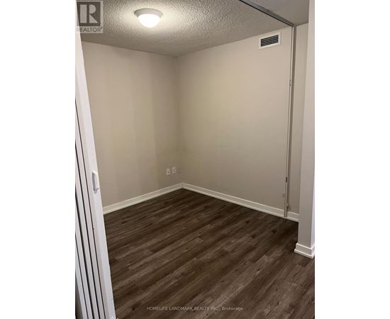 A room with wood flooring and a door on the right side.