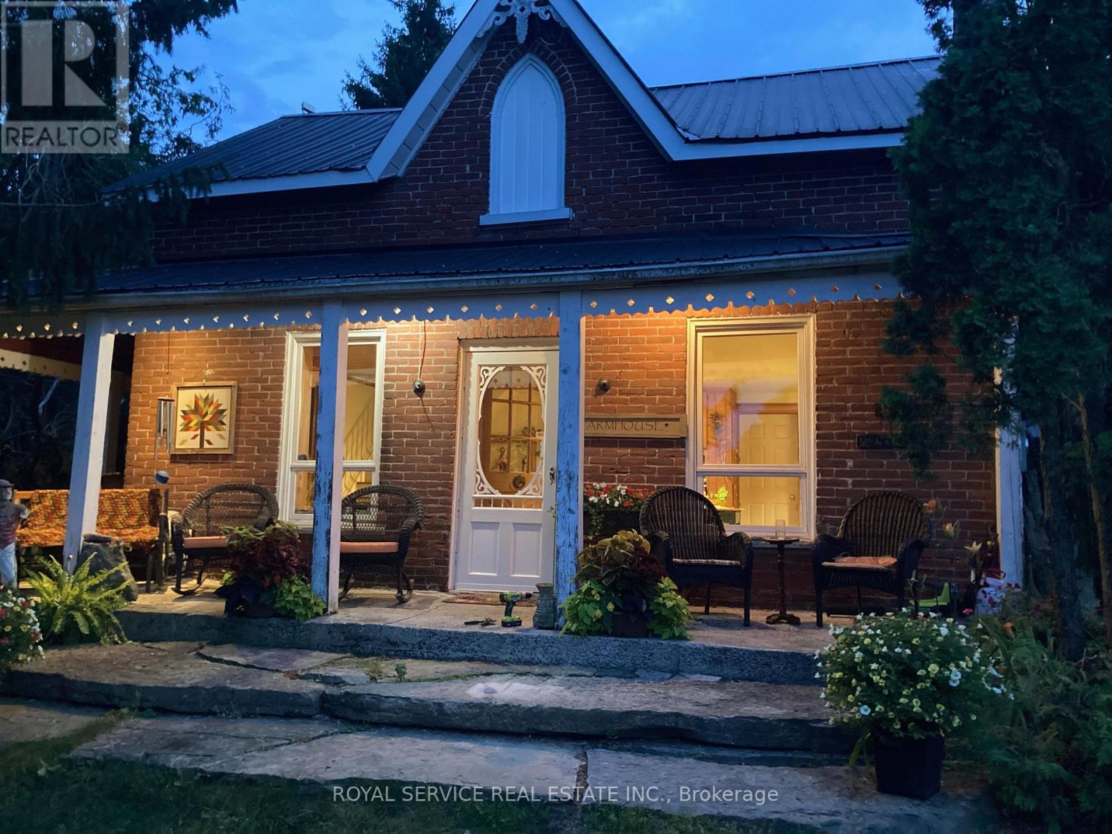 A house with a lit up porch and a sign that says "REALTOR".