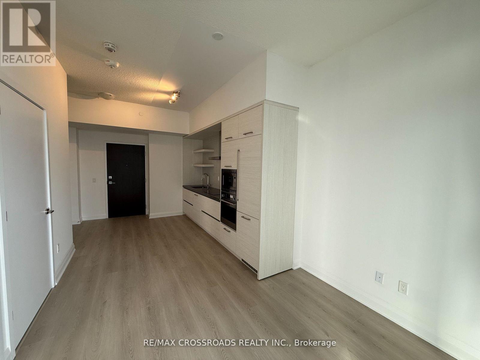 A spacious kitchen with white cabinets and a black refrigerator.