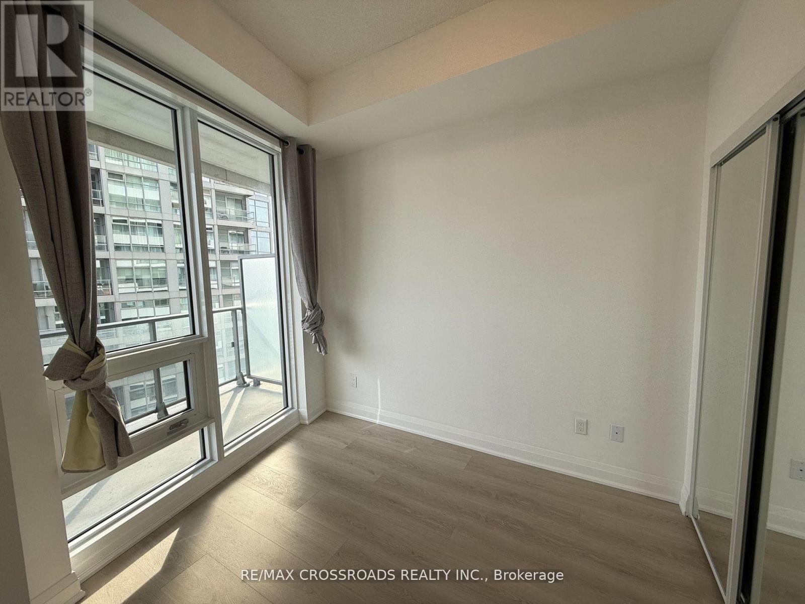 A room with a large window and a view of a building across the street.