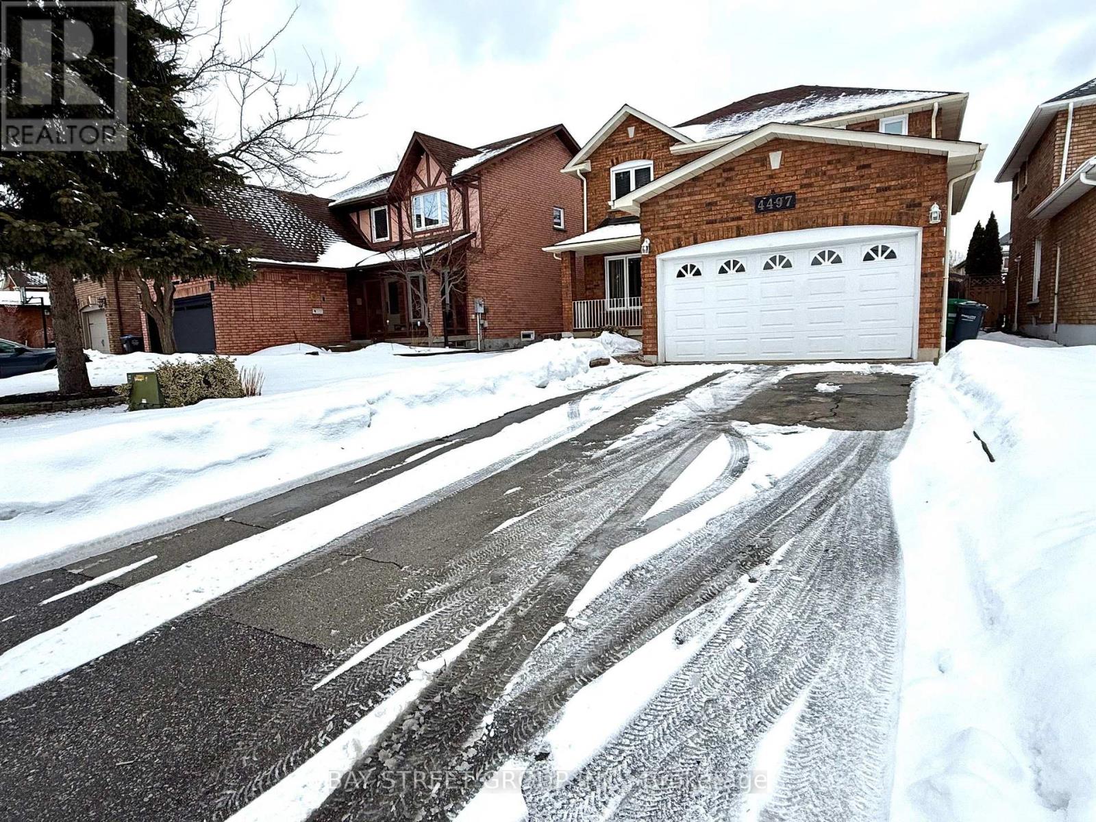A snowy street with a house and garage on the right.