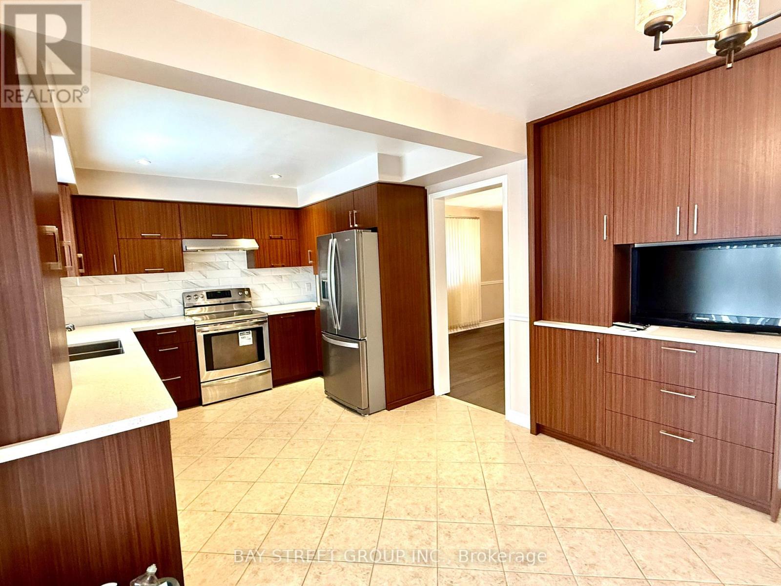 A kitchen with a refrigerator, oven, and sink.