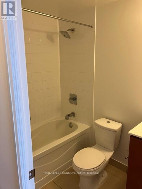 A white toilet in a bathroom with a white shower curtain.