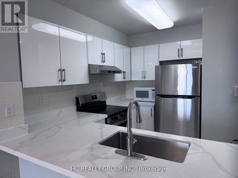 A kitchen with white cabinets and a stainless steel refrigerator.