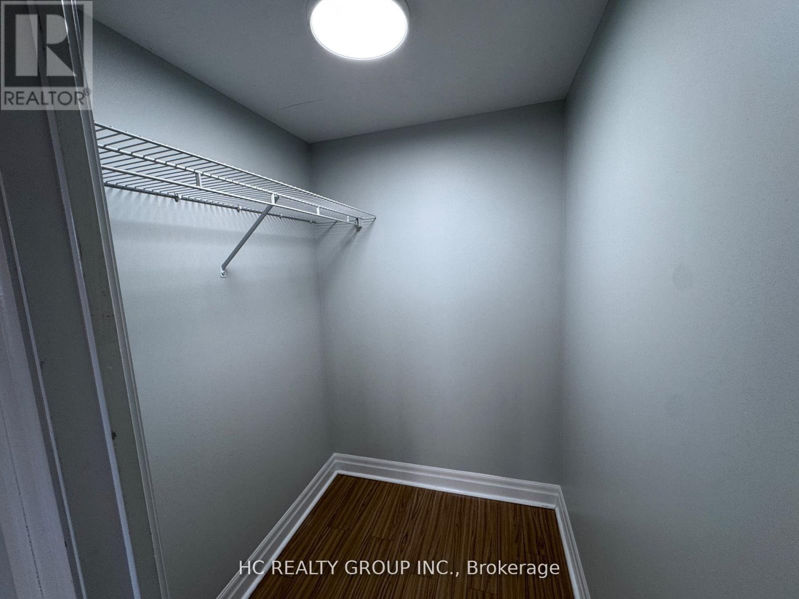 A white wall with a light on and a wooden floor.