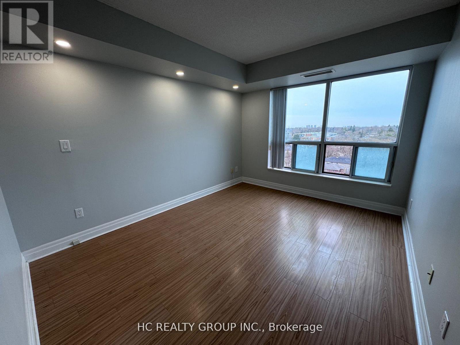 A room with wooden flooring and a large window overlooking a body of water.