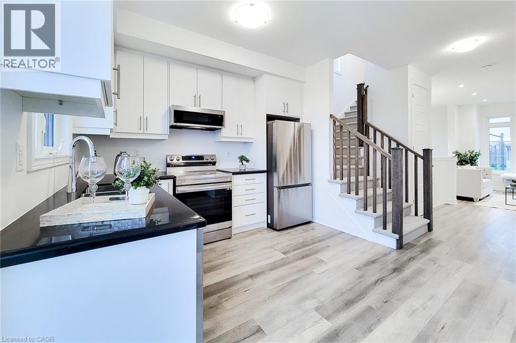 A modern kitchen with white cabinets and a wooden floor.