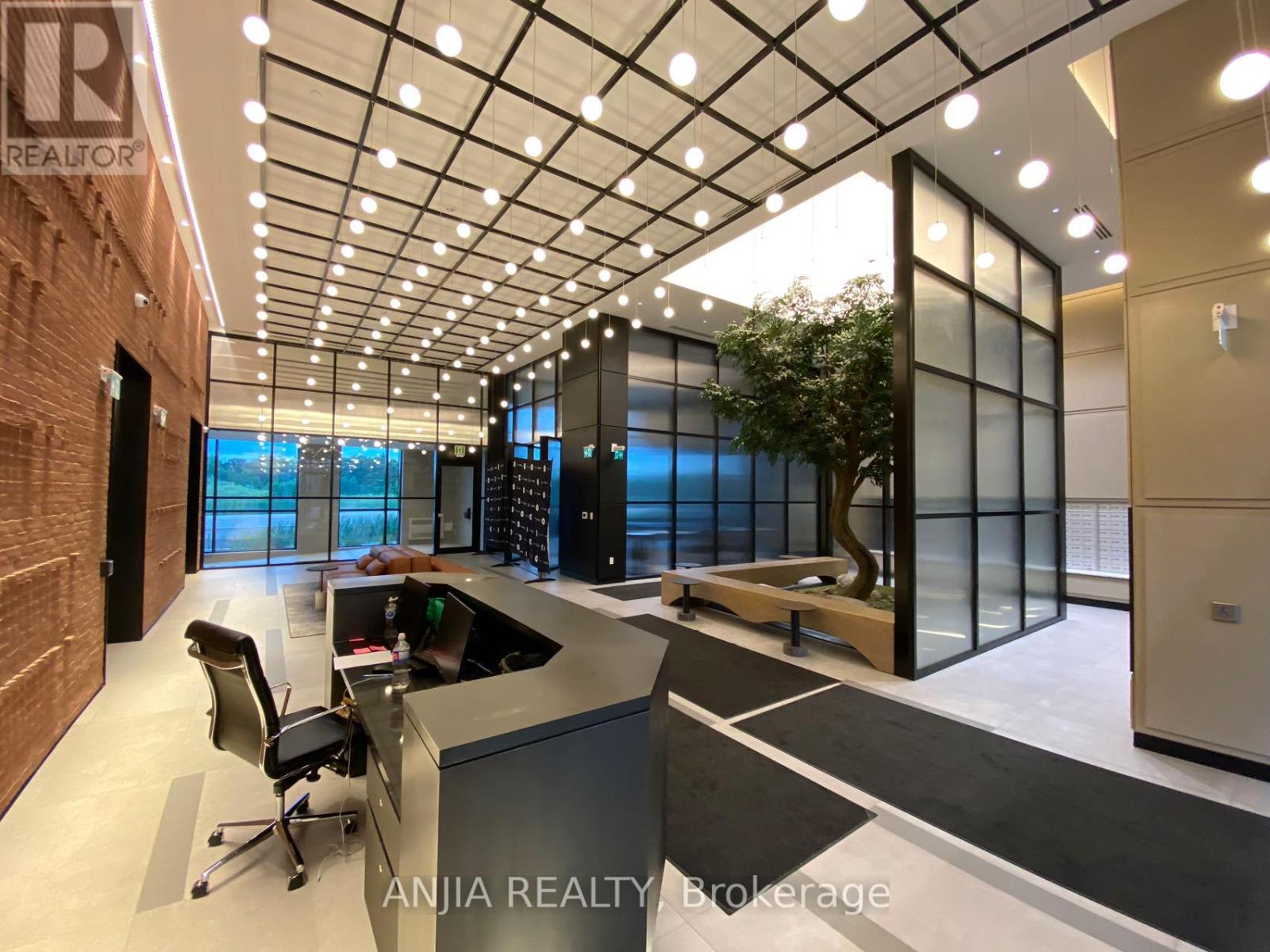 A modern office space with a glass wall and a desk with a computer.