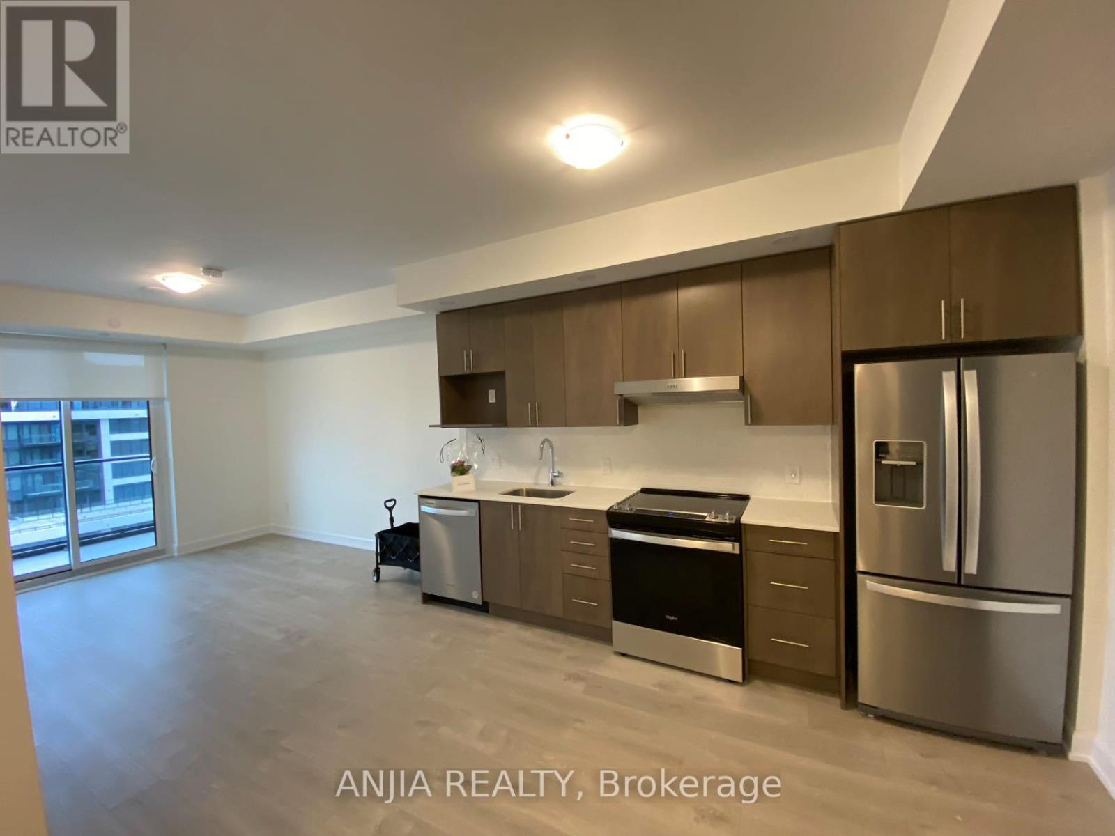 A well-lit kitchen with stainless steel appliances and wooden cabinets.