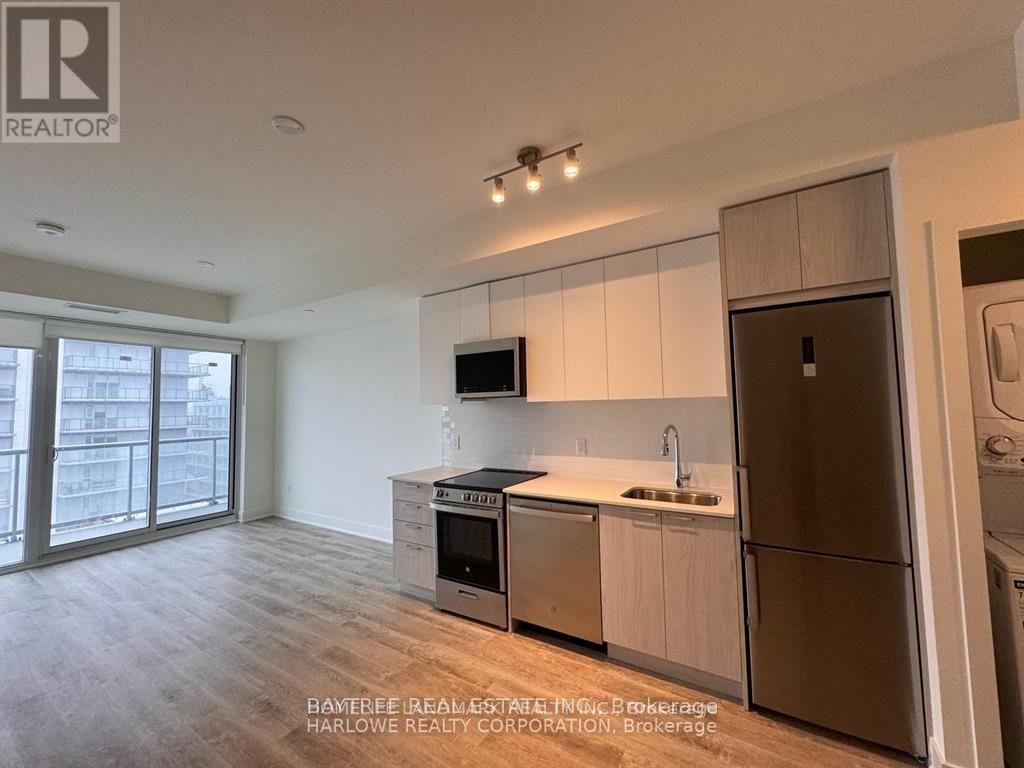 A kitchen with a refrigerator, oven, and sink.