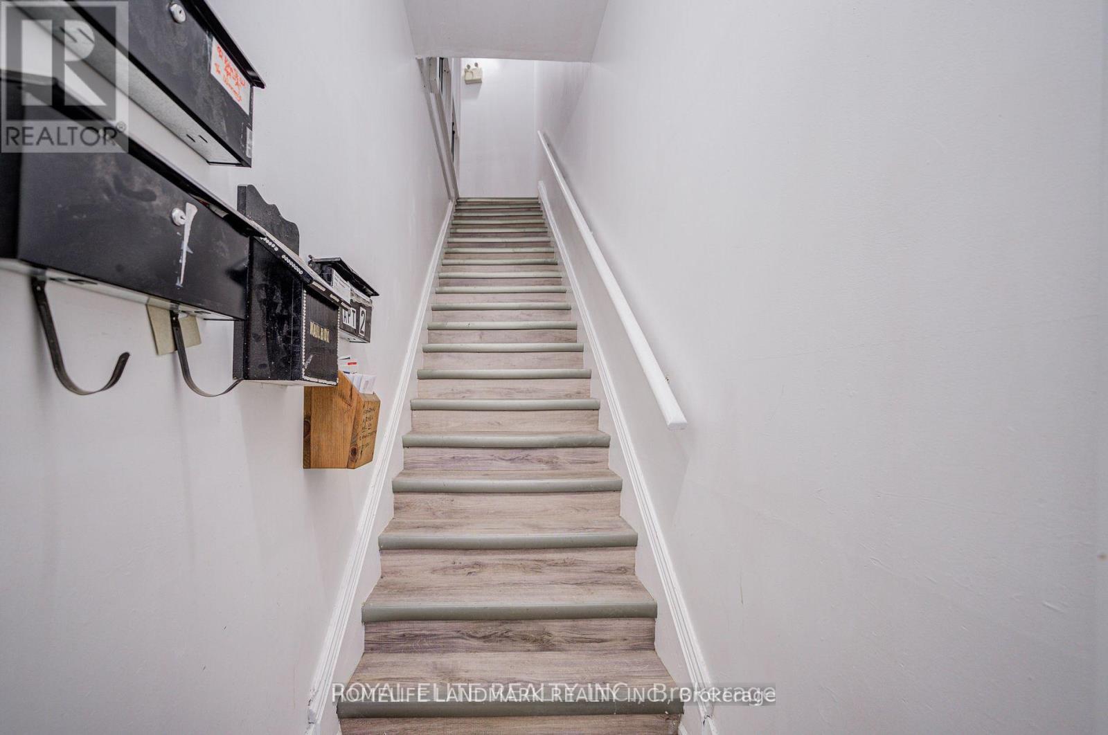 A staircase with a white wall on the side and a black railing on the other side.