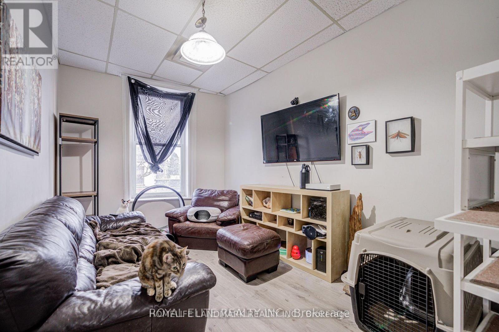 A living room with a brown leather couch and a television on the wall.