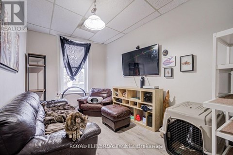 A living room with a brown leather couch and a television on the wall.