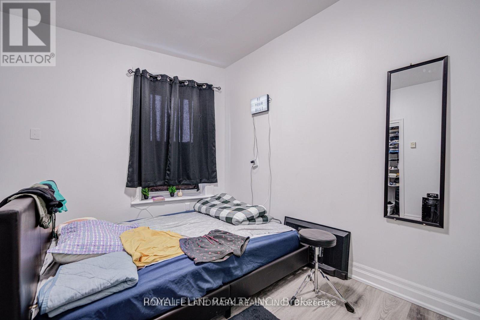 A bedroom with a bed, chair, and mirror.