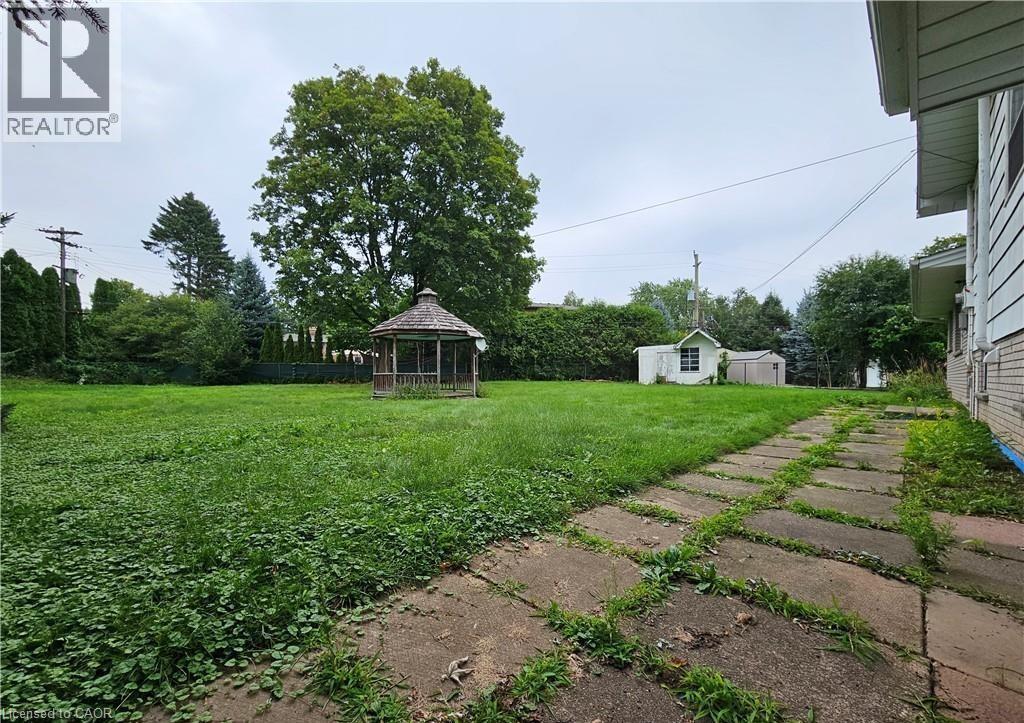 A gazebo sits in a grassy backyard with a house in the background.