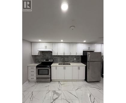A kitchen with white cabinets and marble flooring.