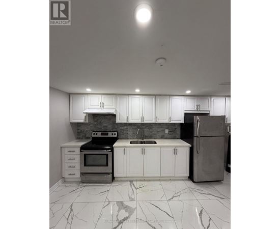 A kitchen with white cabinets and marble flooring.