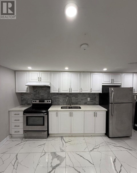 A kitchen with white cabinets and marble flooring.