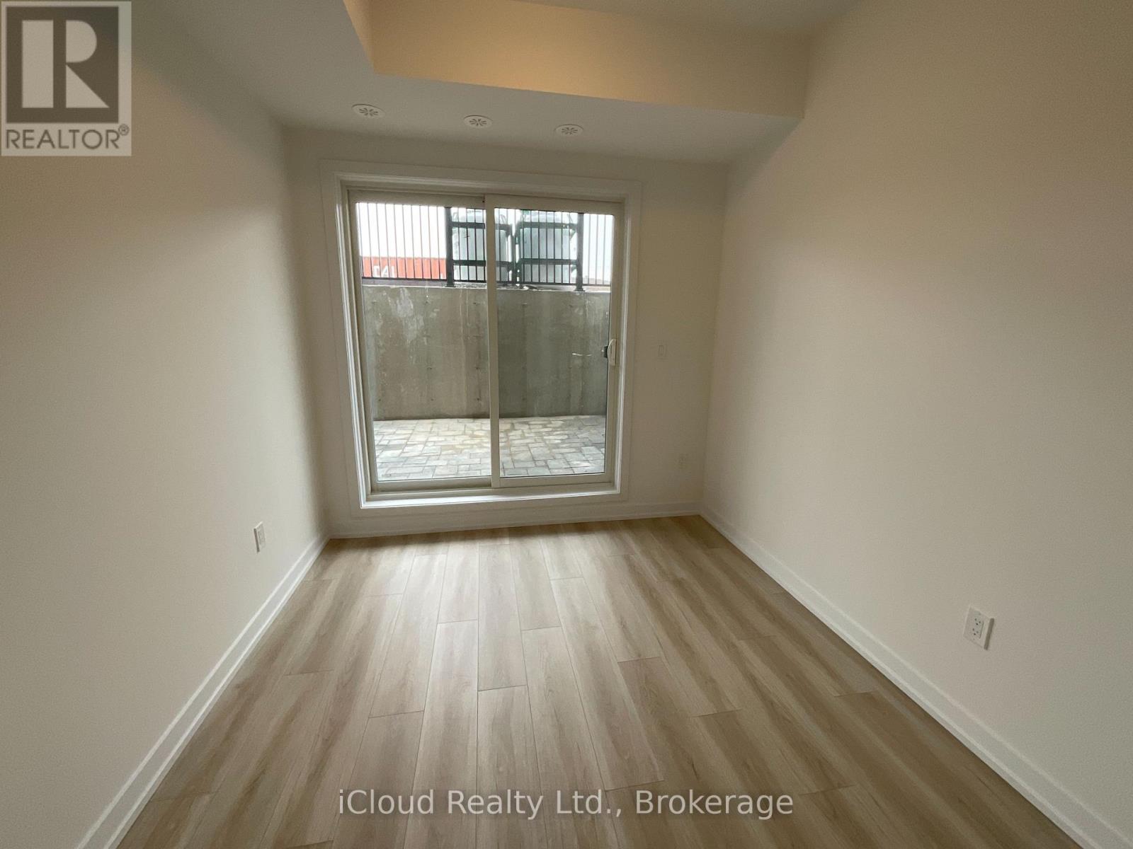 A room with wooden flooring and a glass door leading outside.