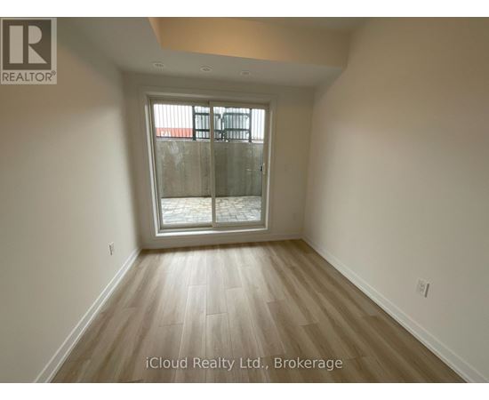 A room with wooden flooring and a glass door leading outside.