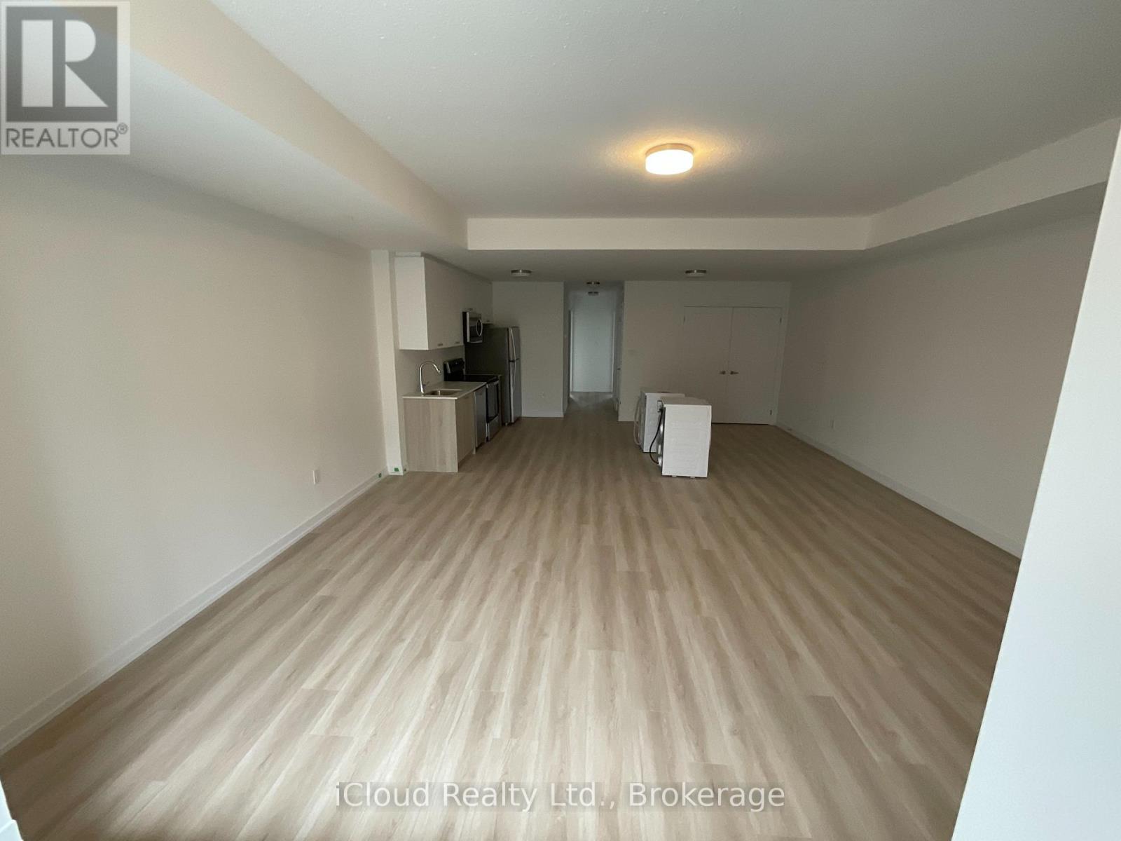 A spacious room with wooden flooring and a refrigerator in the corner.