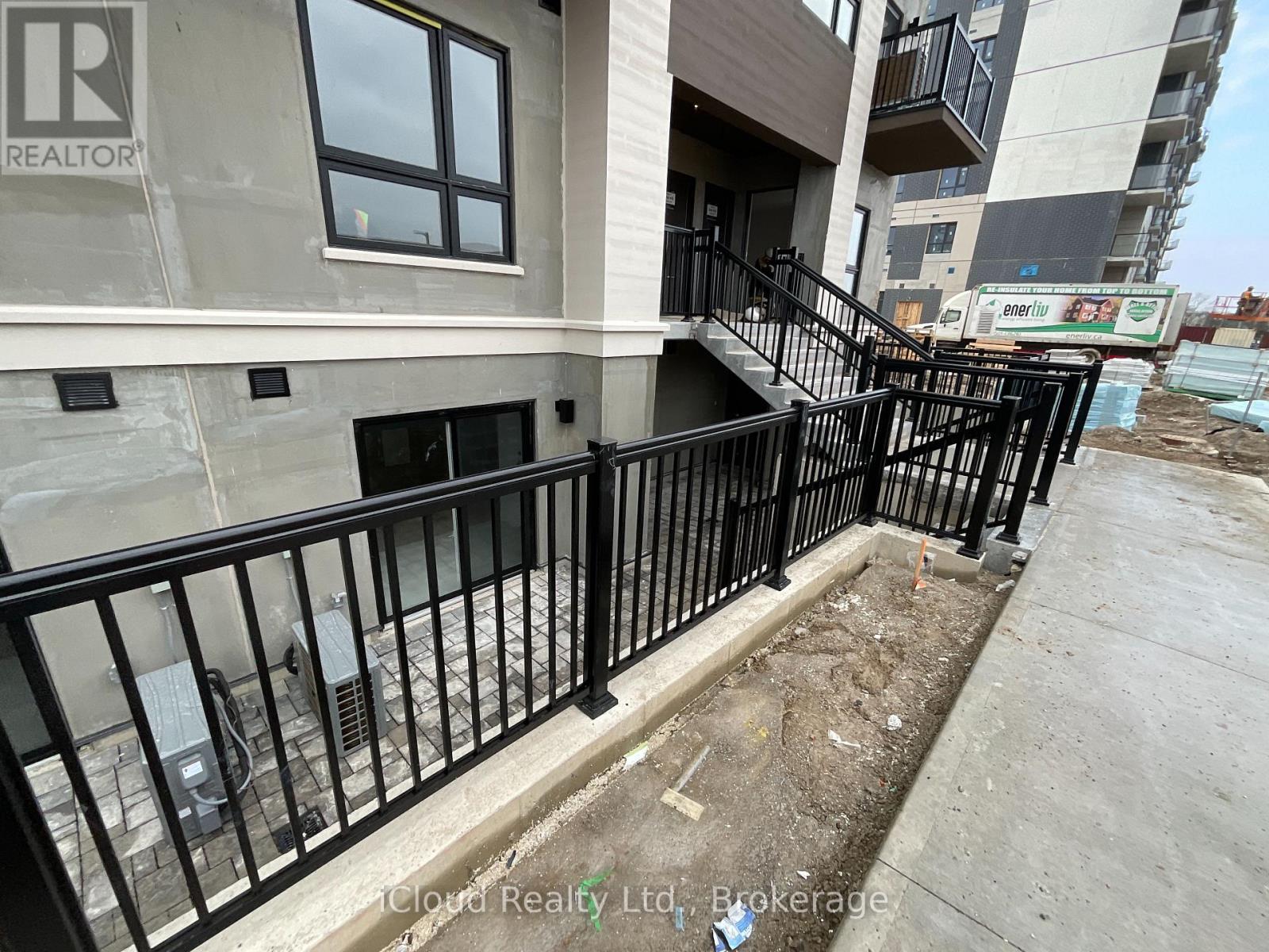 A balcony with a black railing and a building with a window in the background.