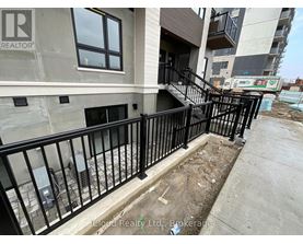 A balcony with a black railing and a building with a window in the background.