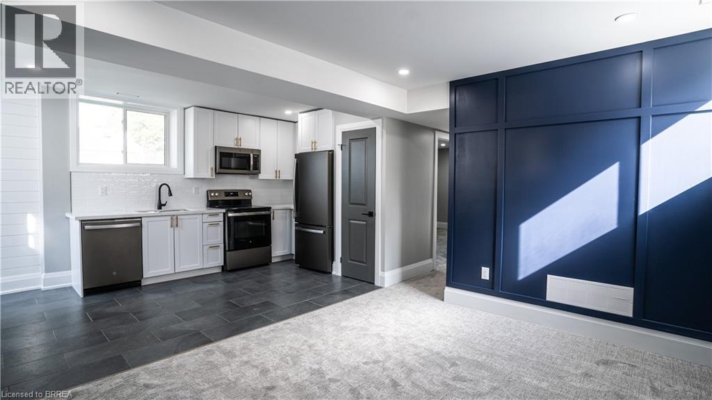A modern kitchen with dark wood floors and white walls.