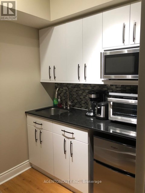 A kitchen with white cabinets and black countertops.