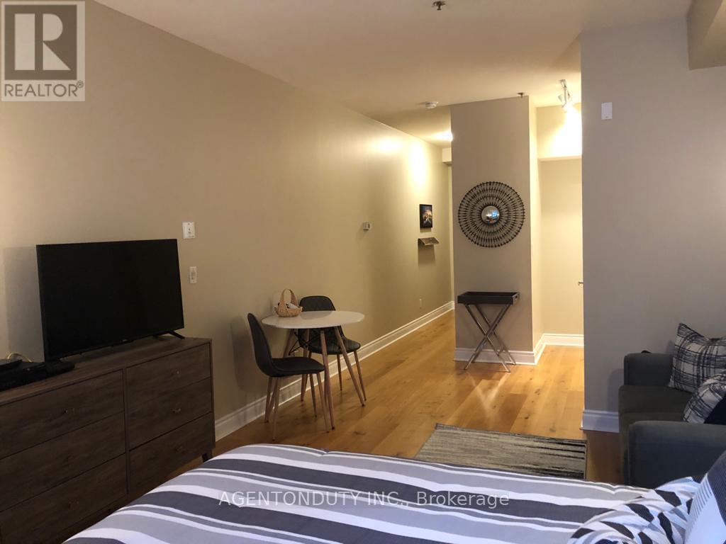 A bedroom with a bed, a table, chairs, and a television.