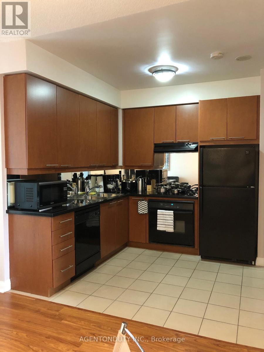 A kitchen with brown cabinets and black appliances.