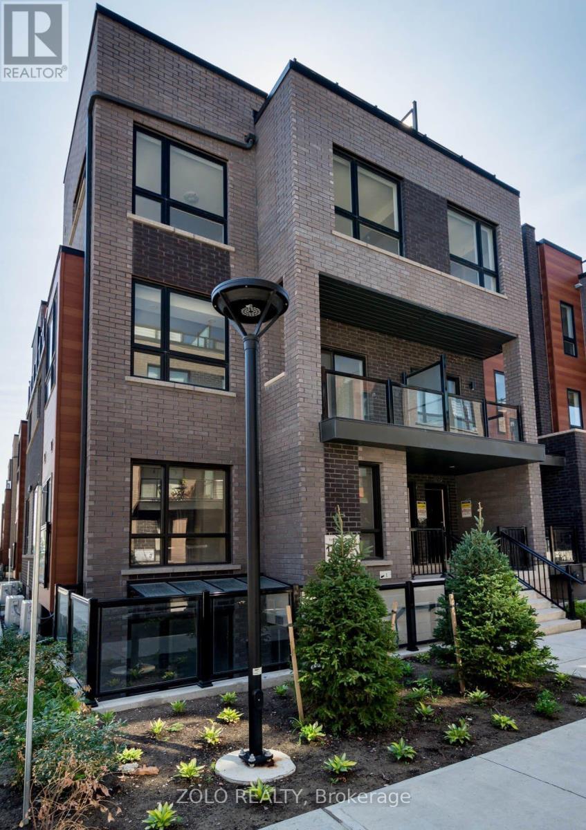 A modern brick building with a balcony and a small garden in front.