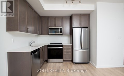 A kitchen with brown cabinets and a stainless steel refrigerator.
