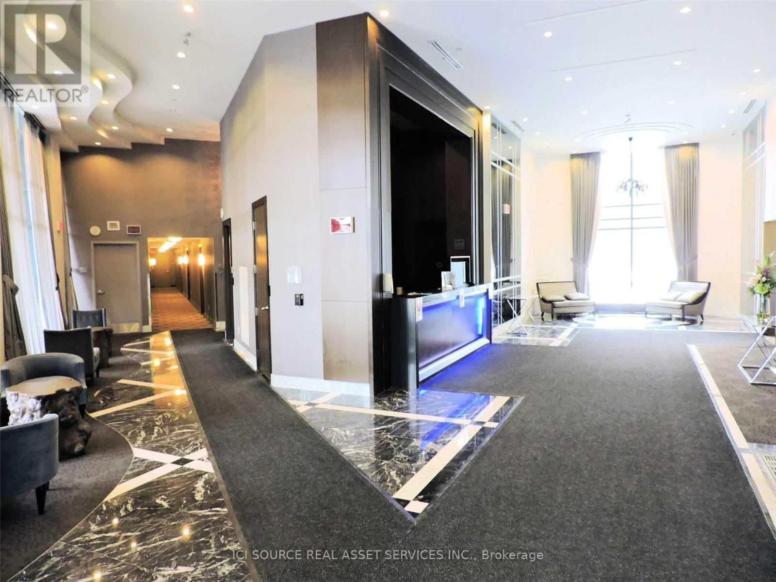 A spacious hotel lobby with a marble floor and a reception desk.