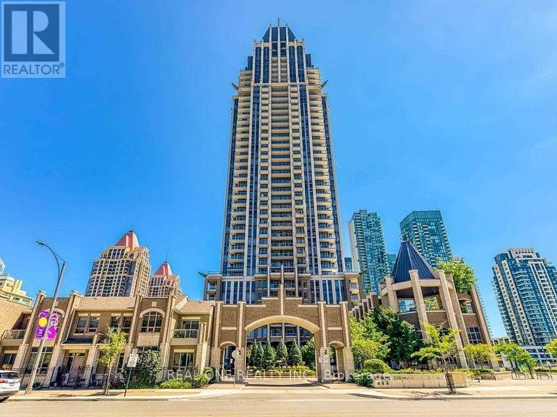 A tall building with a pointed top is in the middle of a city street.