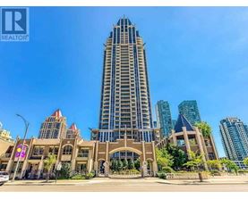 A tall building with a pointed top is in the middle of a city street.