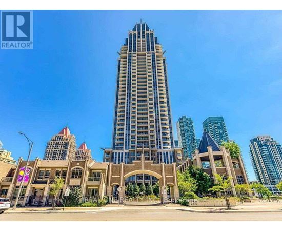 A tall building with a pointed top is in the middle of a city street.
