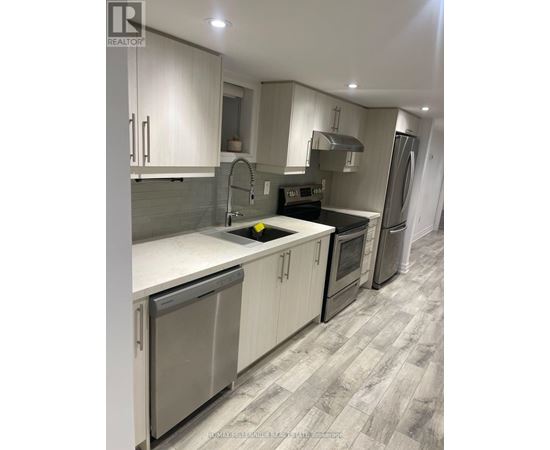 A modern kitchen with white cabinets and a grey floor.