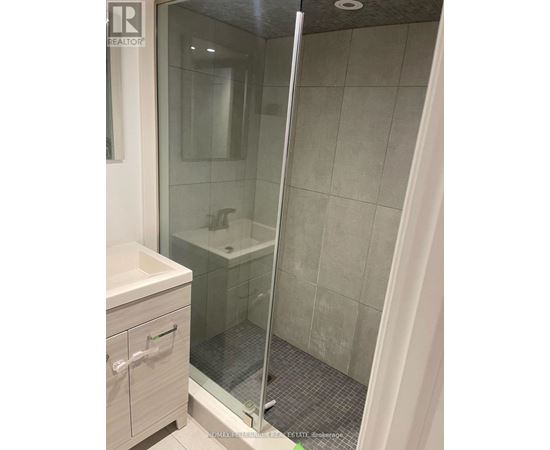A bathroom with a glass shower door and a white sink.