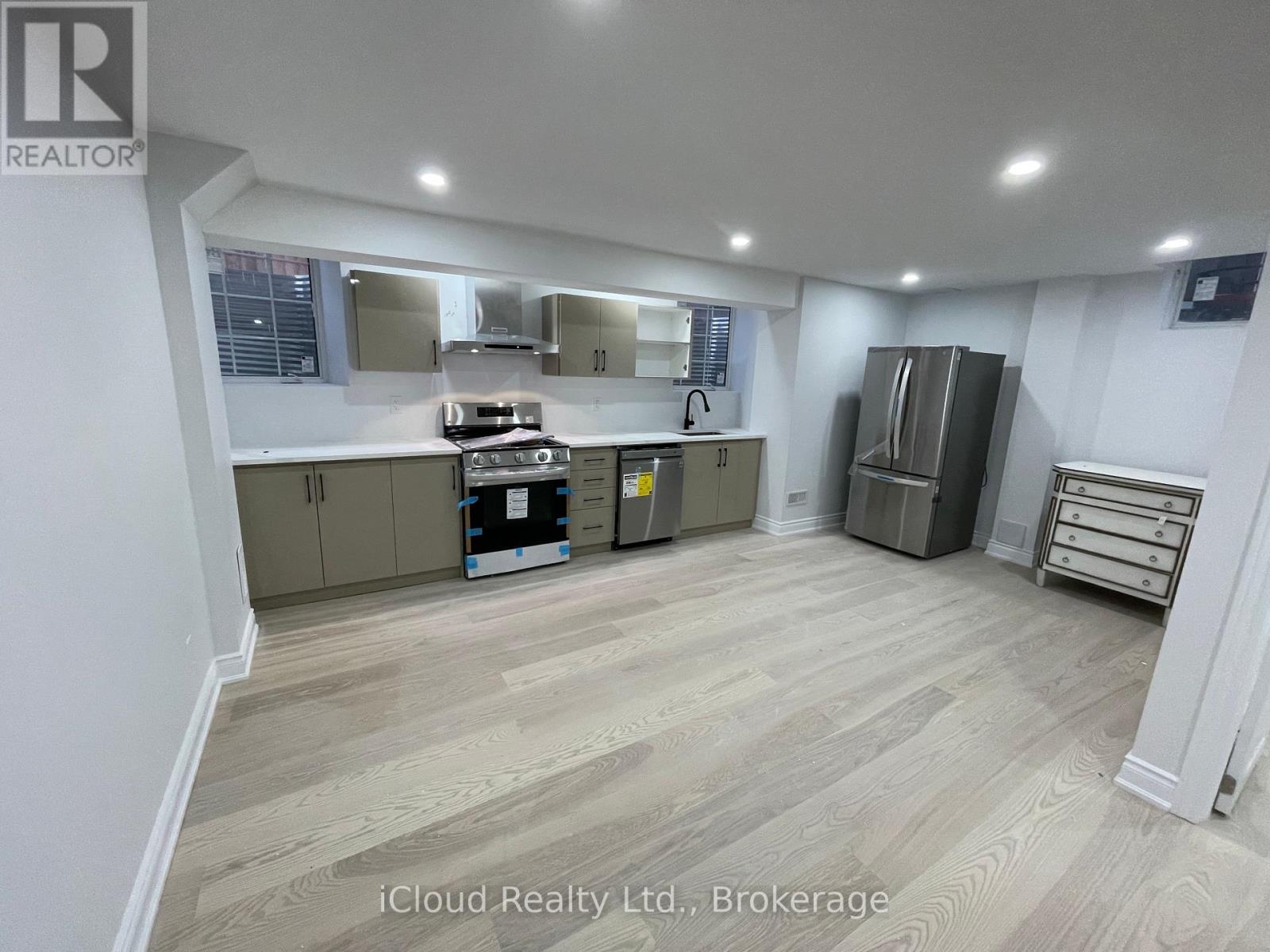 A kitchen with wooden flooring and a refrigerator.