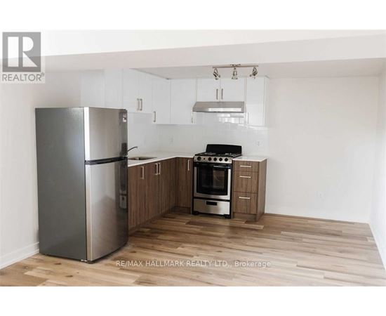 A kitchen with a refrigerator, oven, and cabinets.